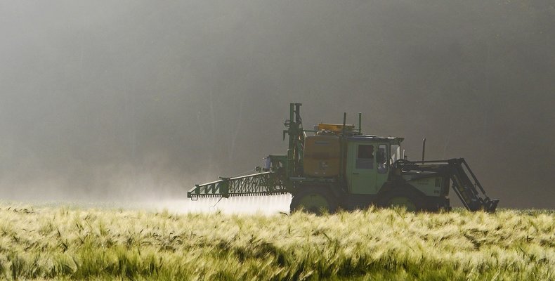Tractor is spraying pesticides on a field