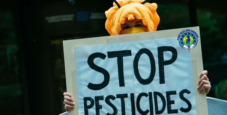 person holds sign with "STOP PESTICIDES" on it